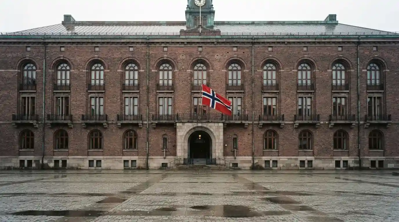 Murfasade av en offentlig bygning i Oslo med et flagg og en tom plass foran, grå himmel
