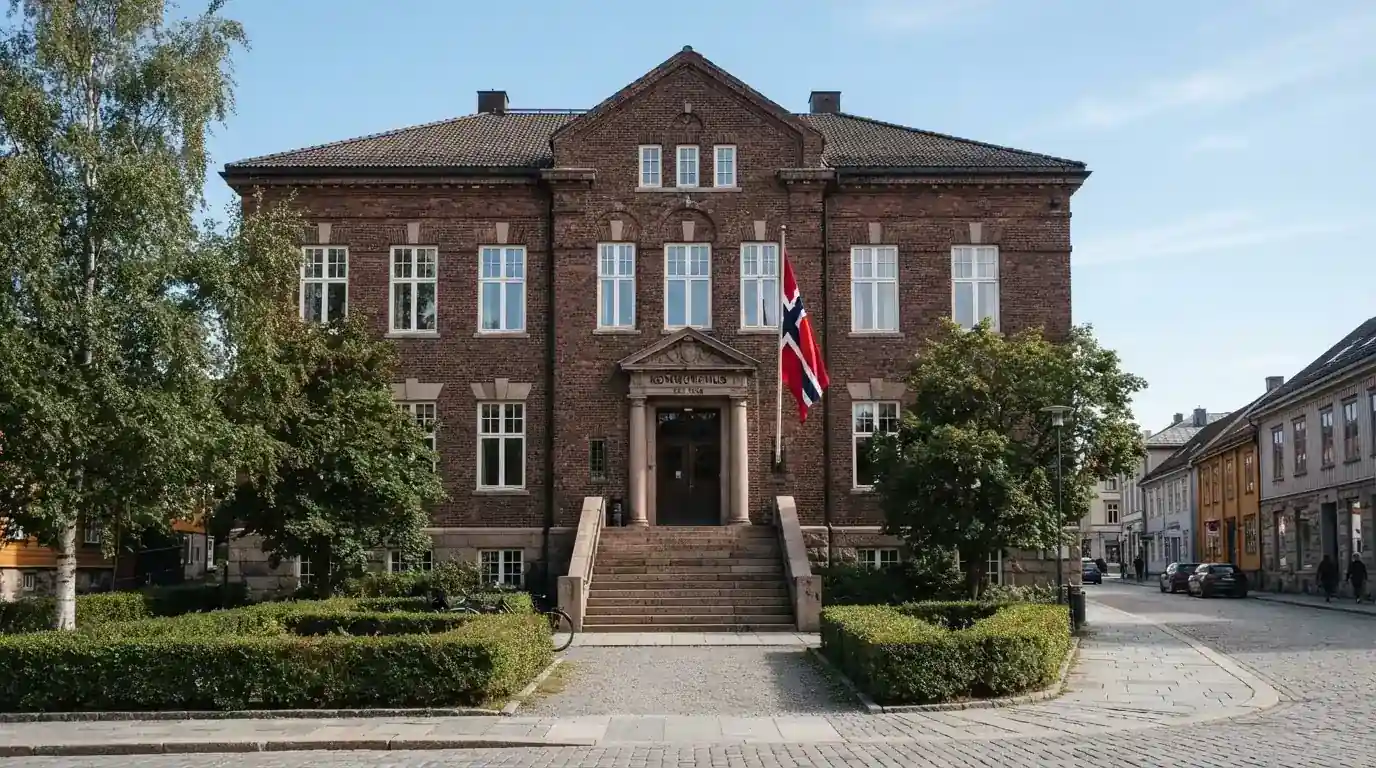 Offentlig kontorbygning i rødt murstein i en norsk by, med et flagg ved inngangen og blå himmel